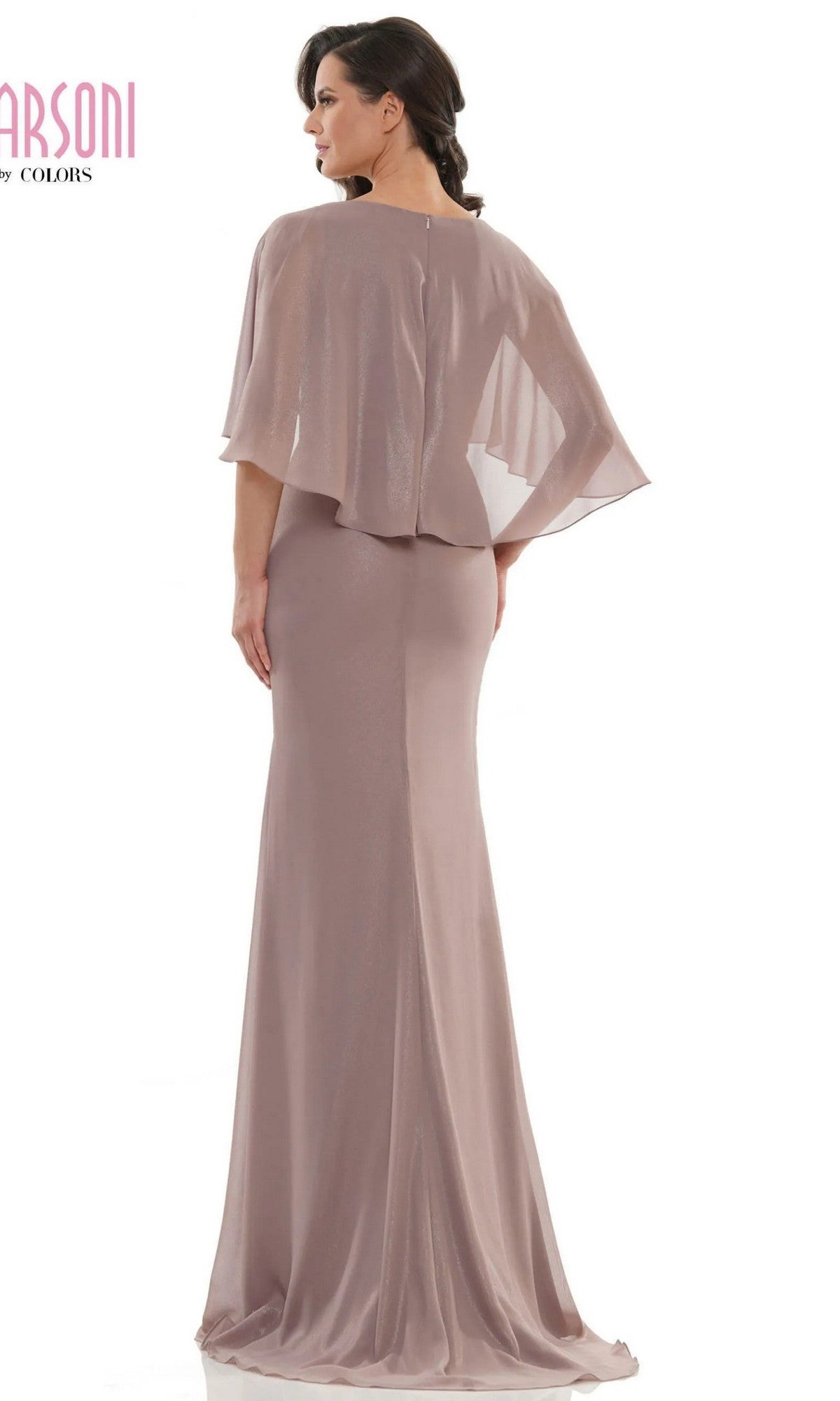 A woman wearing the Marsoni MV1130 long formal dress in mauve, featuring a floor-length design and sheer cape-like overlay, stands facing away from the camera.